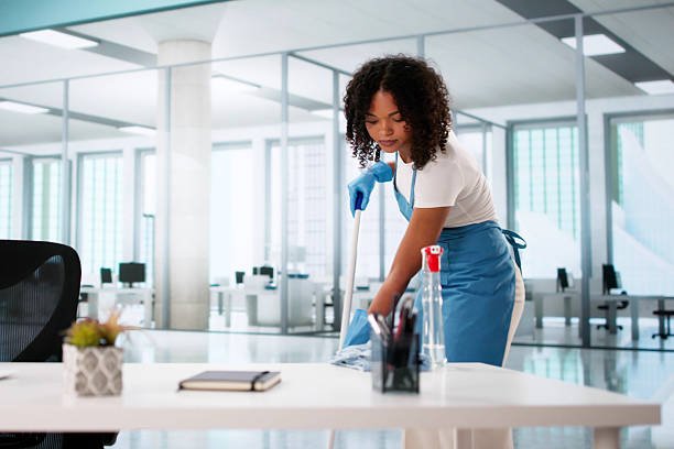 Portrait Of Happy Female Janitor Cleaning Floor At Office